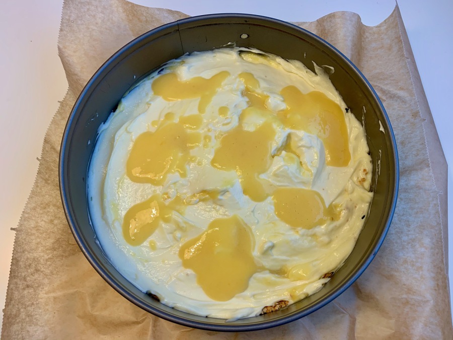 Vanillecreme und 1/3 des Mangopürees auf dem Keksboden verteilen